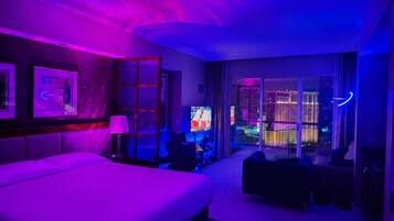 Een hotelkamer met een bed, een bureau, een stoel en uitzicht op de stad.