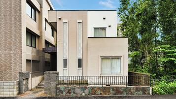 A modern building with a flat roof, a stone base, and a metal railing.
