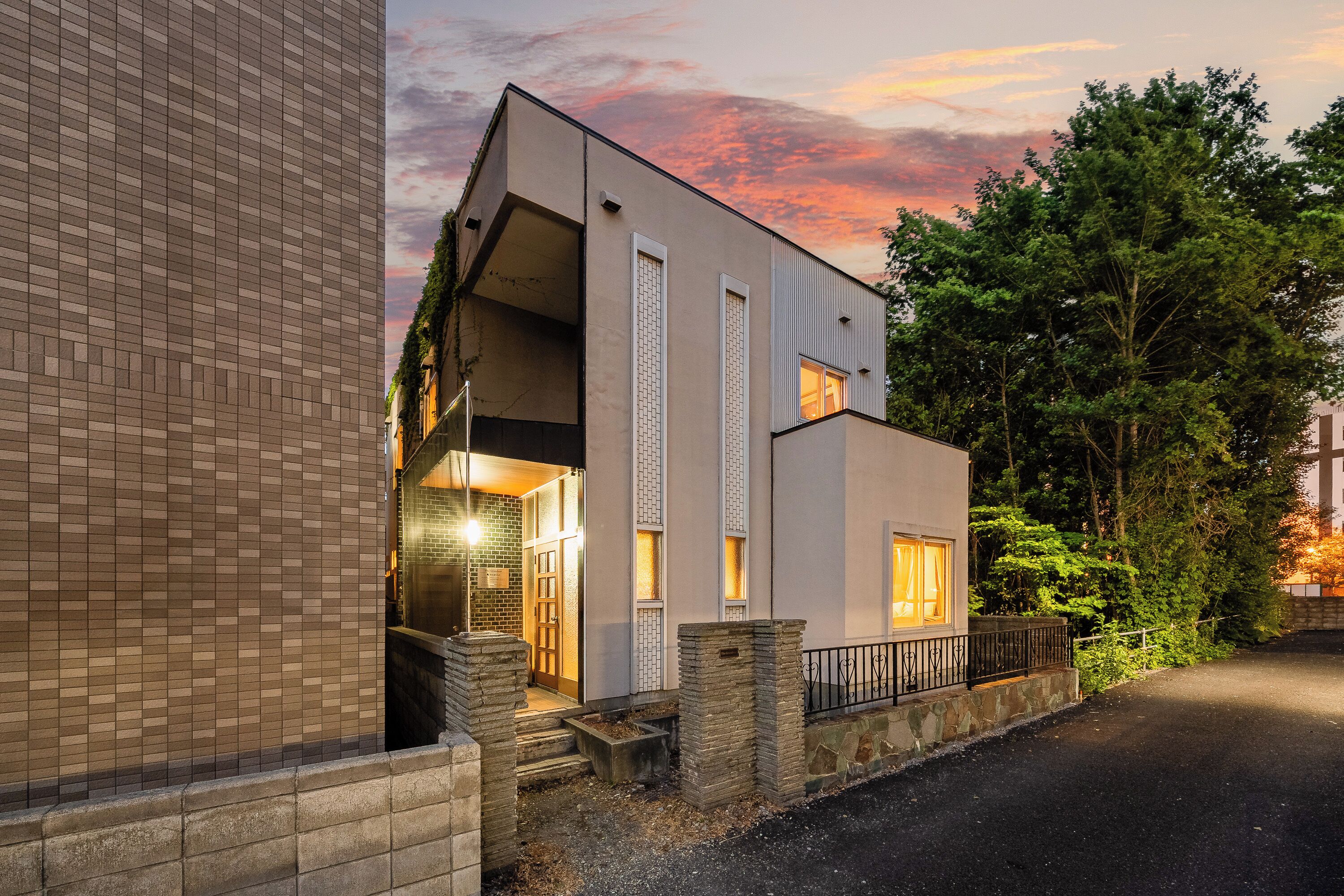 A modern two-story building with a flat roof, large windows, and a stone base.