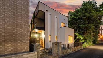 A modern two-story building with a flat roof, large windows, and a stone base.