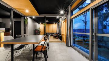 A modern conference room with a long table, chairs, and a large window offering a view of the outdoors.