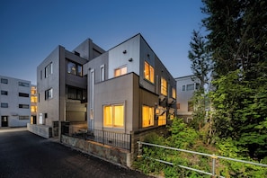 A modern multi-story building with balconies, large windows, and a stone base.