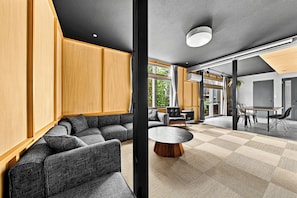 A modern living room with a sectional sofa, a round coffee table, and a dining area with a table and chairs.