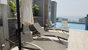 A rooftop pool area with lounge chairs and an umbrella. - Peru & Barranco, Food and History (Barranco)