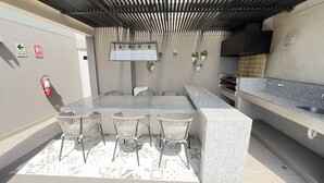 An outdoor kitchen area with a granite countertop, four wicker chairs, a fire extinguisher, and a grill. - Peru & Barranco, Food and History (Barranco)