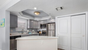 Une cuisine moderne avec des meubles gris, des appareils en acier inoxydable et un îlot central blanc.