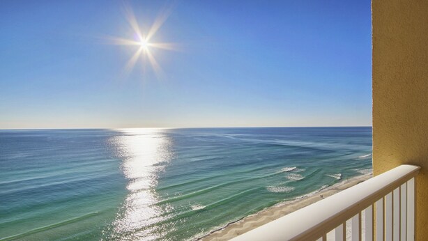 A balcony with a view of the ocean and a clear sky.