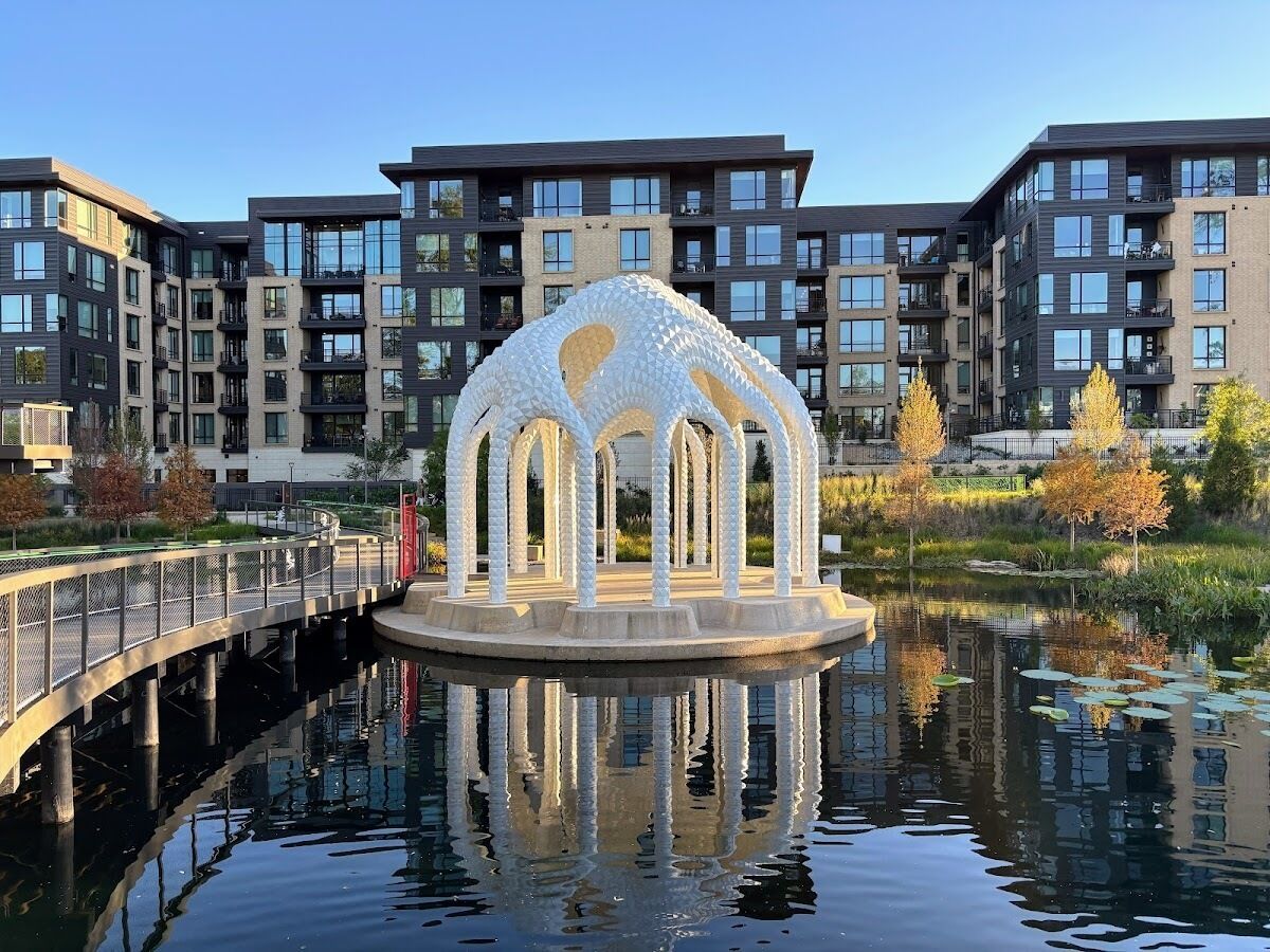En modern byggnadskomplex med en central fontän och en gångbro för fotgängare.