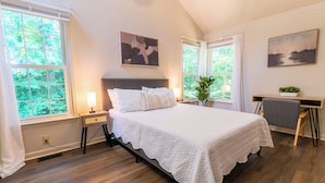 Un dormitorio con una cama grande, un escritorio y dos ventanas.