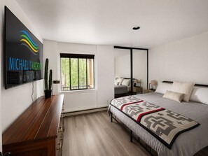 Une chambre à coucher moderne avec un lit, un bureau, une fenêtre et un miroir.