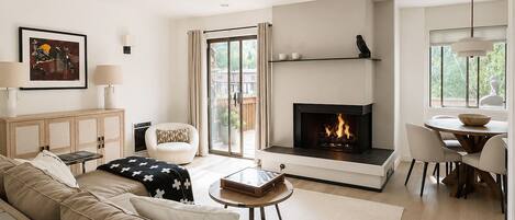 A modern living room with a fireplace, a sofa, a coffee table, and a dining area.