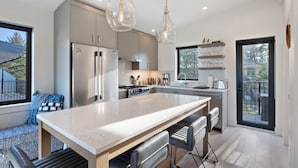 A modern kitchen with a central island, stainless steel appliances, and pendant lighting. - Saratoga Sands at THE BEACH HOUSE (Campbell River)