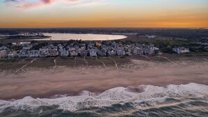 Ein Küstenwohngebiet mit Häusern direkt am Strand, einem sandigen Strand und einem Gewässer im Hintergrund.