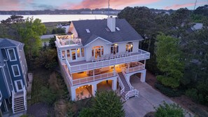 Een tweelaags huis met een balkon, een trap en uitzicht op een waterpartij.