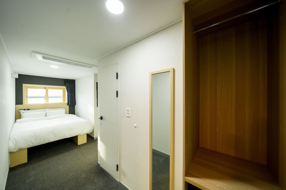 A bedroom with a bed, a wardrobe, and a mirror.
