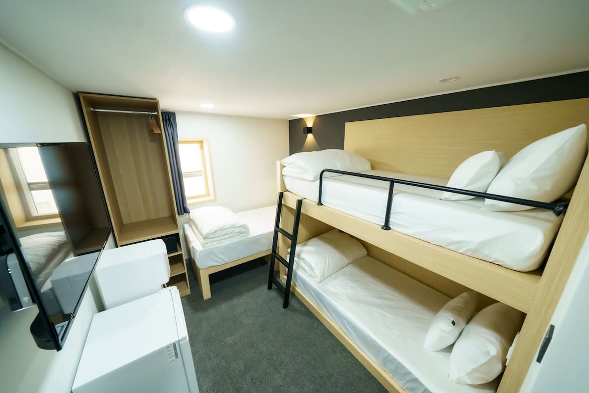 A bunk bed room with a desk and a wardrobe.