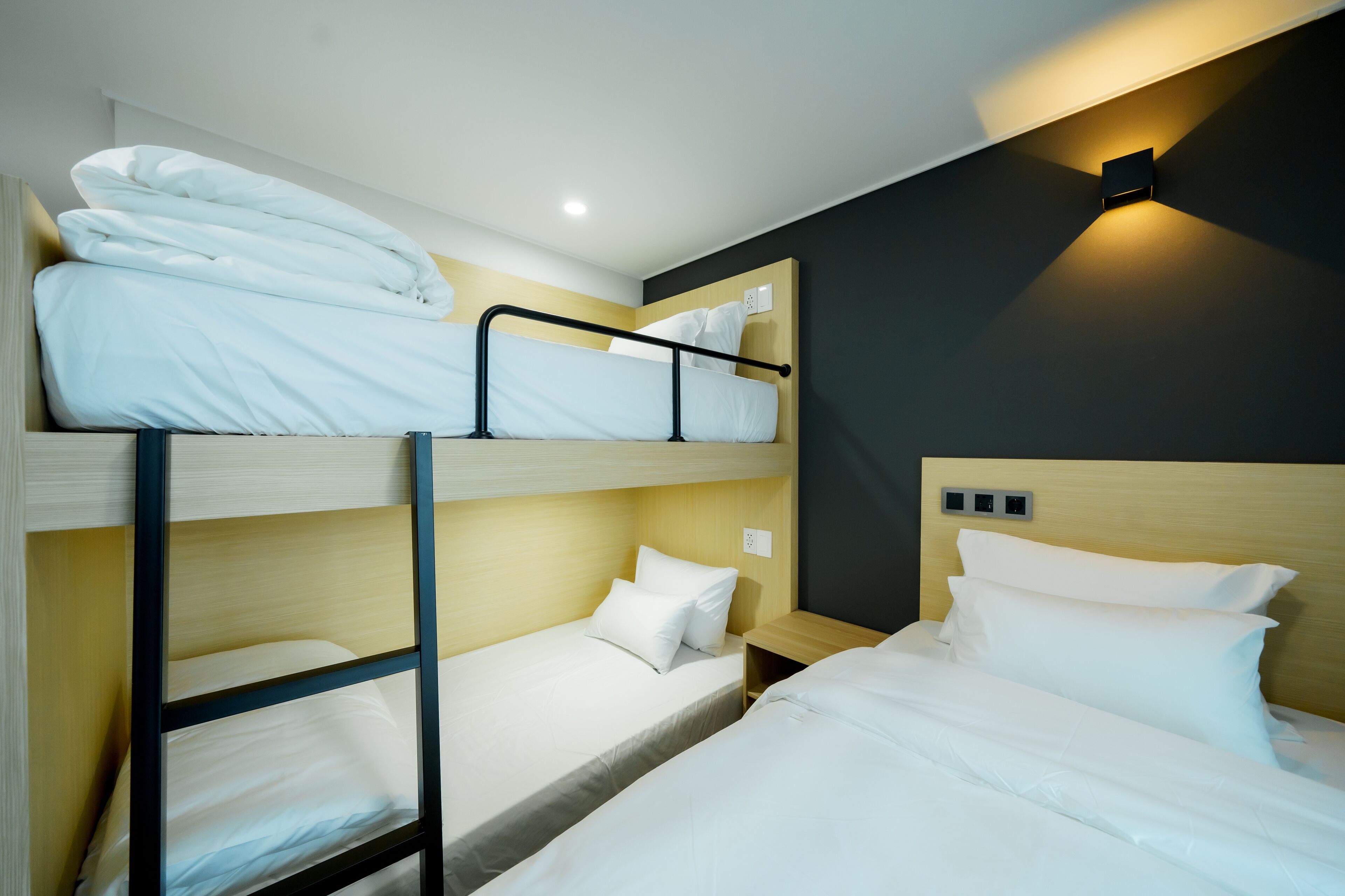 A bunk bed room with a wooden headboard, a bedside table, and a wall-mounted light fixture.