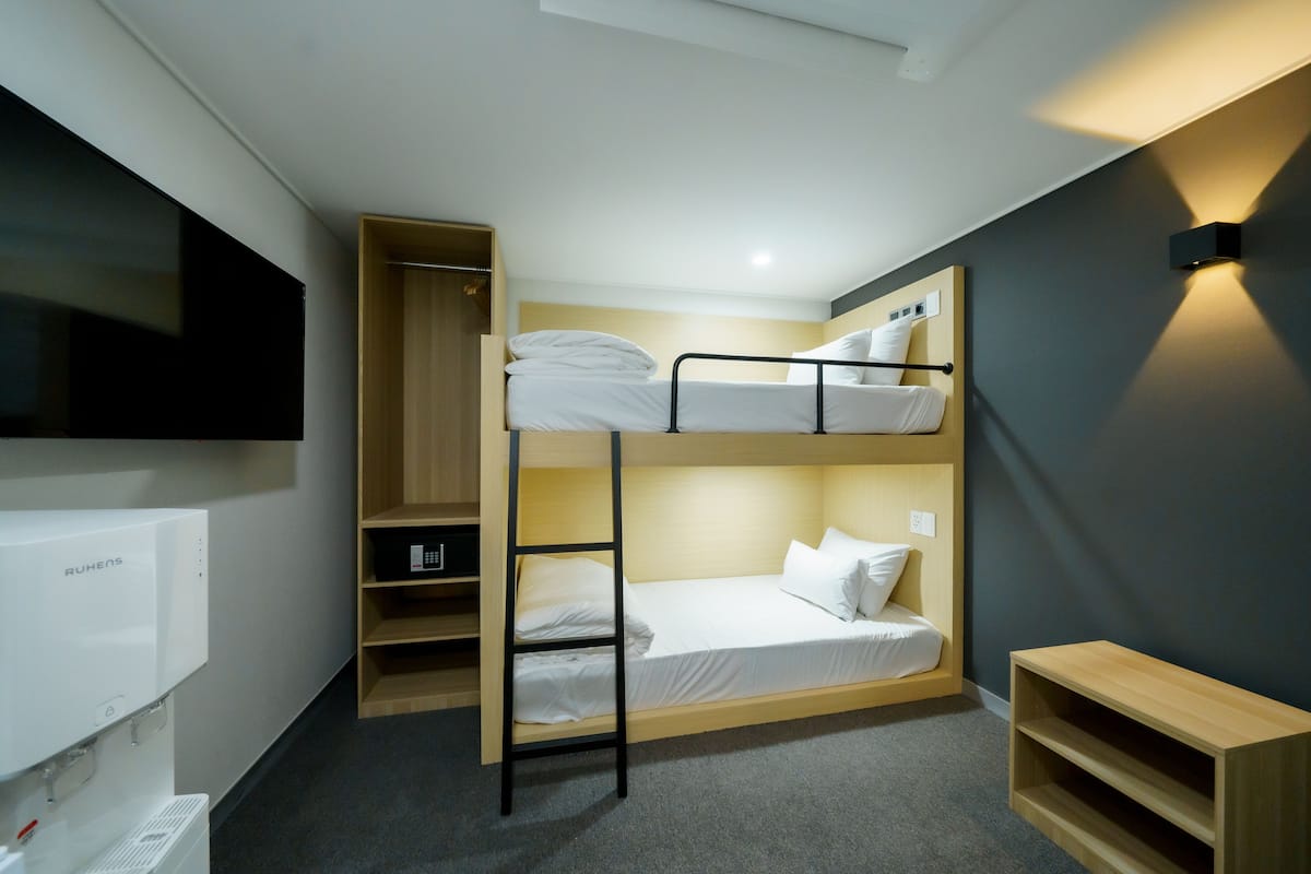 A bunk bed room with a TV, a heater, and a shelf.