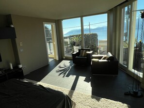 Een moderne hotelkamer met een groot bed, een sofa en een balkon met uitzicht op zee.