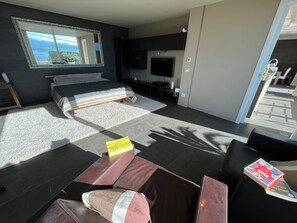 A modern bedroom with a bed, a TV, and a large window.
