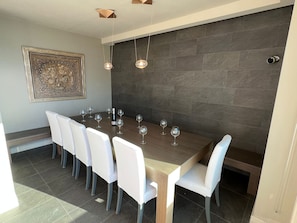 A dining area with a long table, six chairs, and several wine glasses.