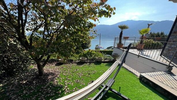 Een hangmat op een groen gazon met uitzicht op een meer en bergen.
