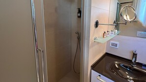 Een moderne badkamer met een douchecabine van glas, een wastafel en een spiegel.