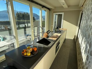 Une cuisine moderne dotée d’un grand îlot central, d’un évier et offrant une vue sur les montagnes par les fenêtres.