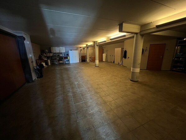 Un pasillo amplio con suelo de baldosas, columnas y puertas de acceso a habitaciones.