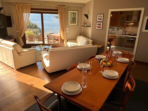 A modern living room with a dining area, a sofa, a coffee table, and a view of the outdoors.