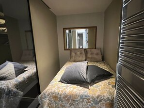Une chambre à coucher avec un lit, deux oreillers, un miroir et une fenêtre.