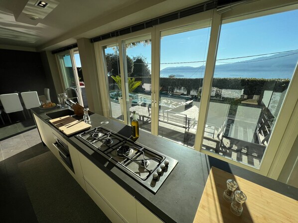 A modern kitchen with a gas stove, a cutting board, and a bottle of olive oil.