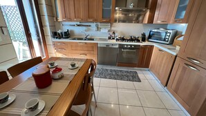 Een moderne keuken met houten kastjes, roestvrijstalen apparatuur en een eethoek met een tafel gedekt voor twee personen.