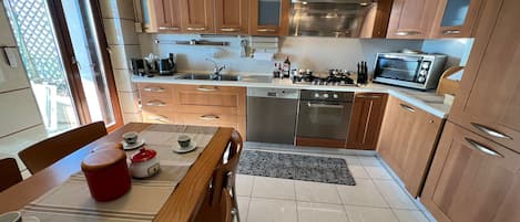 A compact kitchen with wooden cabinets, stainless steel appliances, and a dining area with a table set for two.