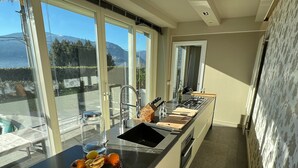 Une cuisine moderne dotée d’un grand îlot central, d’un évier intégré et offrant une vue sur les montagnes grâce à de grandes fenêtres.