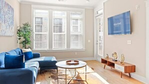 A modern living room with a sofa set, a coffee table, and a TV mounted on the wall.