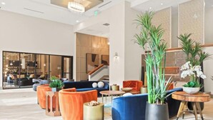 A modern lobby with a mix of seating areas, including sofas and armchairs, and a staircase leading to an upper level.
