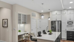 A modern kitchen with white cabinets, a stainless steel refrigerator, and pendant lighting. - Reluxme | 2BR Condo in Center City w/ Spa Access (Charlotte)