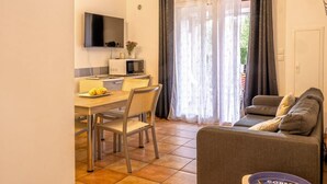 A compact living space with a dining area, a sofa, and a television. - Casarella Massari (Oletta)