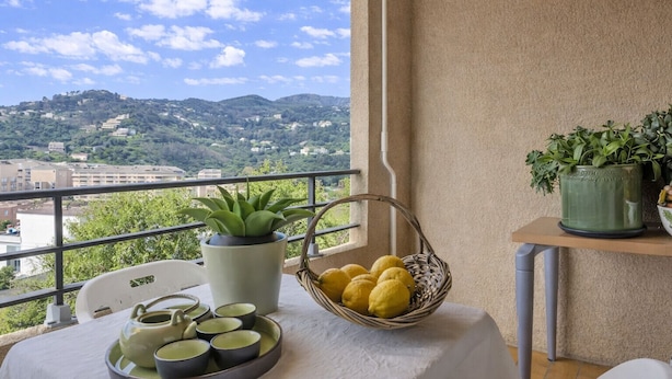 Un balcone con un tavolo apparecchiato per il tè, un cesto di limoni e una pianta in vaso.