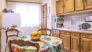 Una cucina con pensili in legno, un forno a microonde e una ciotola di frutta sul piano di lavoro.
