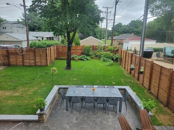 A backyard with a patio table and chairs, surrounded by a wooden fence and a grassy lawn. - EVANSTON whole building, 2 units combined sleeps 12, 5 bed 5 bath (Evanston)