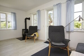A room with two grey armchairs, a black heater, and a floor lamp. - Haus Schwedentraum - Gemütliches Haus mit Kamin, Sauna, Garten und Terrasse - Haus Schwedentraum (Wiek)