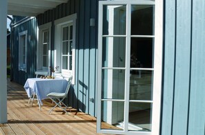 A covered outdoor area with a table and chairs, a window, and a door.