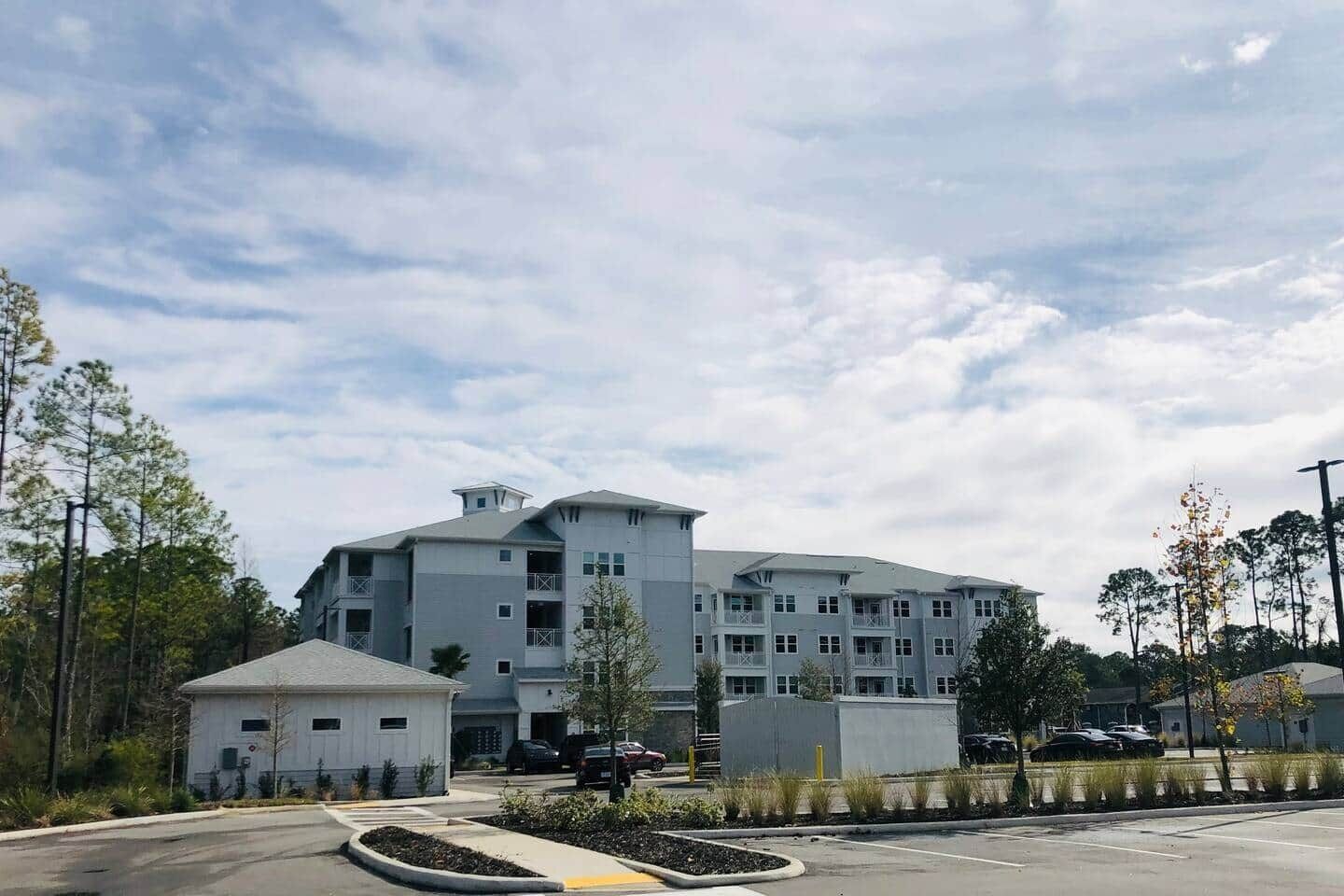 A multi-story hotel with a parking lot in front.
