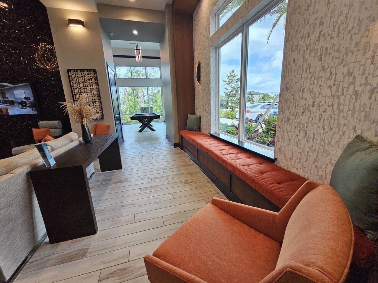 Ein modernes Wohnzimmer mit Holzboden, einer Couch, einer Bank und einem Essbereich mit Billardtisch.