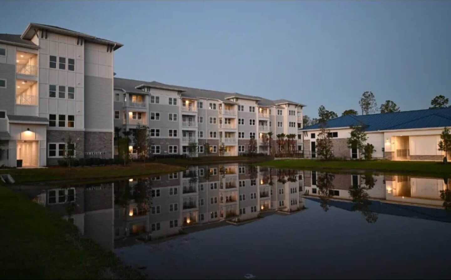Ein mehrstöckiges Hotel mit einem Pool, der die Umgebung spiegelt.