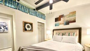 Un dormitorio con una cama grande, un armario, un espejo y un cuadro en la pared.