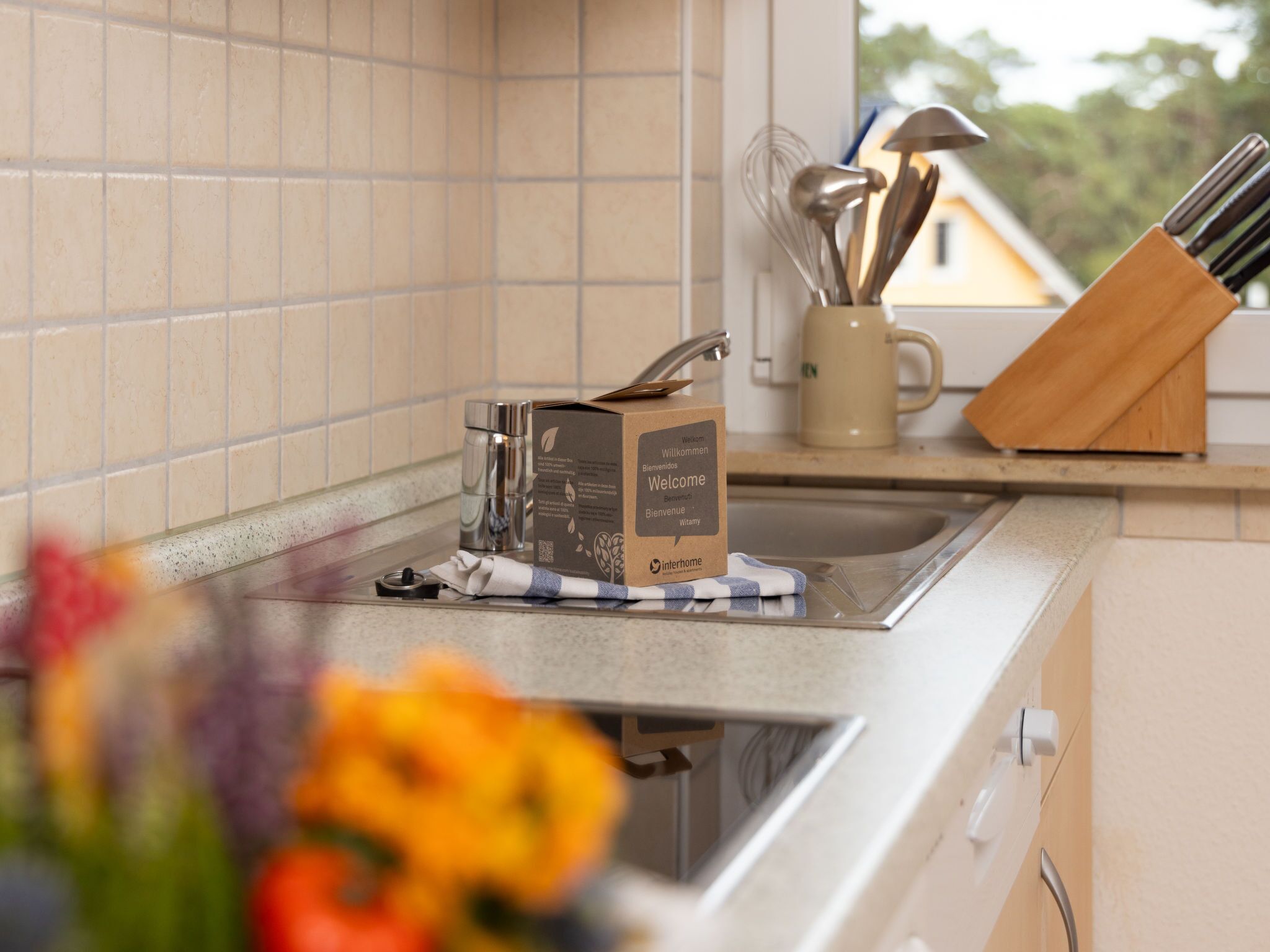 Eine Küchenarbeitsplatte mit einer Kaffeemaschine, einer mit ‚Willkommen‘ beschrifteten Schachtel und einem Messerblock.