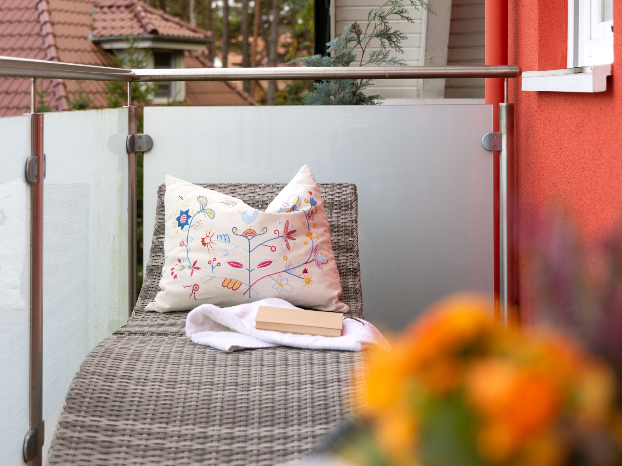 Ein Korbstuhl mit Kissen und Buch auf einem Balkon.